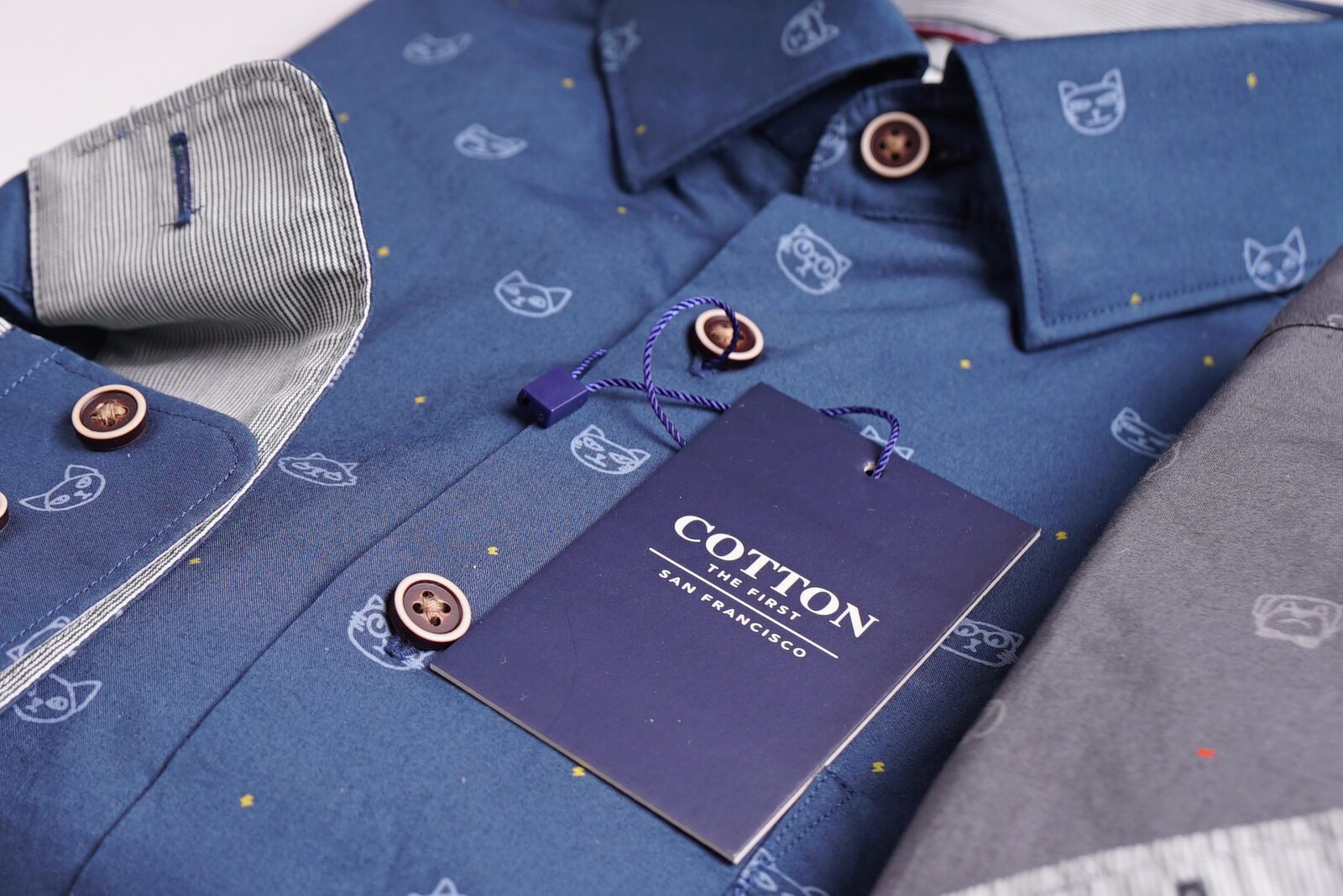 Cotton the First SPCA shirt closeup — blue colorway with cat and dog print, brand tag